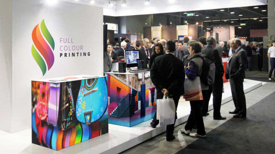 Full Colour Printing exhibition SEG stand with colorful graphics and attendees.