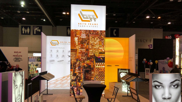 Brite Frame Fabricators expo booth with illuminated signage and display samples.